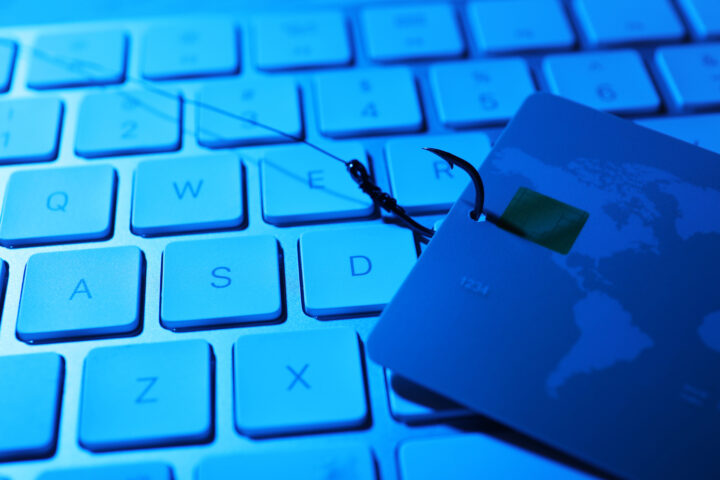 IT Phishing graphic with credit card hooked by fishing line on top of computer keyboard