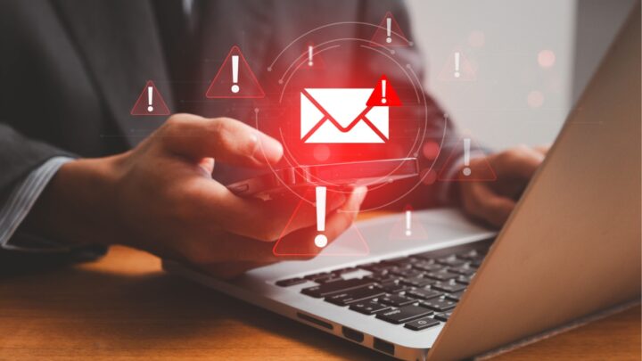 Business professional using a smartphone and laptop while receiving phishing alerts, illustrating the growing threat of business email compromise and email-based cyber attacks.