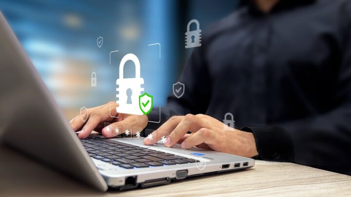 Person using a laptop with digital padlock and shield icons representing cybersecurity, secure access and data protection.